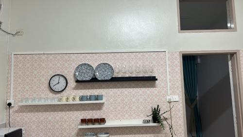 a wall with a clock and a shelf with glasses at The Hidden 7 in Taiping