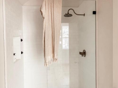 a white bathroom with a shower with a glass door at Homestead Barn Loft in Sonora