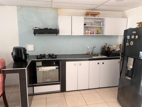 a kitchen with white cabinets and a black refrigerator at Descansa con tranquilidad in Villavicencio