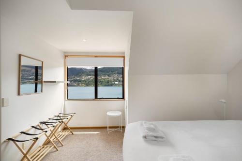 a white room with a bed and a window at Lakefront Cottage in Queenstown