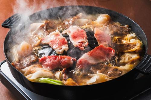 a pan full of food with meat and vegetables at Takamiya Hotel Lucent in Zao Onsen