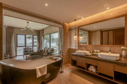 baño con 2 lavabos y bañera grande en KOI Resort & Residence Da Nang en Da Nang