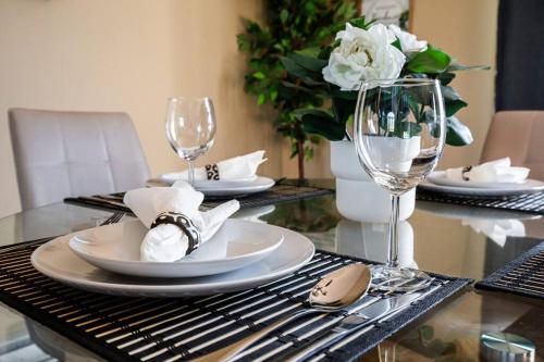 a table with plates and glasses and a vase with flowers at Le Cozy Clover in Moncton