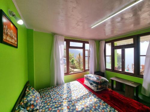 a bedroom with green walls and a bed and windows at Neoravalley Homestay, Icche Gaon in Pedong