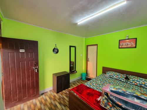 a bedroom with green walls and a bed and a door at Neoravalley Homestay, Icche Gaon in Pedong