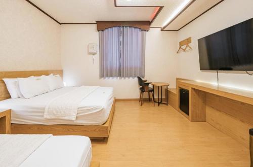 a hotel room with two beds and a flat screen tv at CF Motel in Jeju