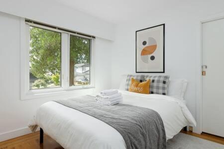 a white bedroom with a bed and a window at Spacious 3 bedroom property in North Vancouver in North Vancouver