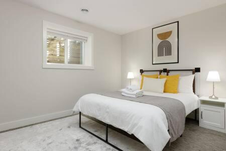 a white bedroom with a bed and a window at Bright new 1 BR private secondary basement suite in North Vancouver