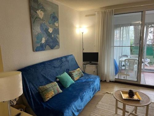 un salon avec un canapé bleu et une table dans l'établissement Appartement Rez-de-Chaussée, Terrasse, Proche Tennis, Parking, Animaux Acceptés, Capacité 5 Personnes - FR-1-749-42, au Cap d'Agde
