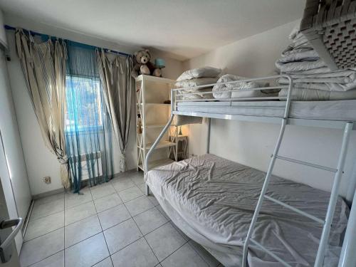 une chambre avec deux lits superposés et une fenêtre dans l'établissement Pavillon T3 avec Piscine, Terrasse et Jardin à Valras-Plage - 6 Pers, 900m de la Mer - FR-1-701-75, à Valras-Plage