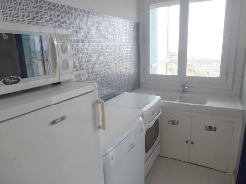 - une cuisine blanche avec un four micro-ondes et un évier dans l'établissement Location Studio Spacieux - Proche Plage et Commerces - Animaux Admis - FR-1-323-416, à Saint-Jean-de-Monts