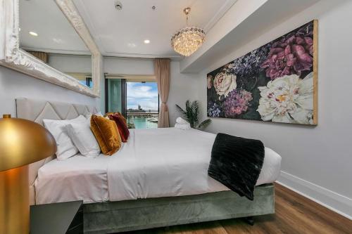 a bedroom with a white bed with a large painting on the wall at The Sunset Suite in Auckland