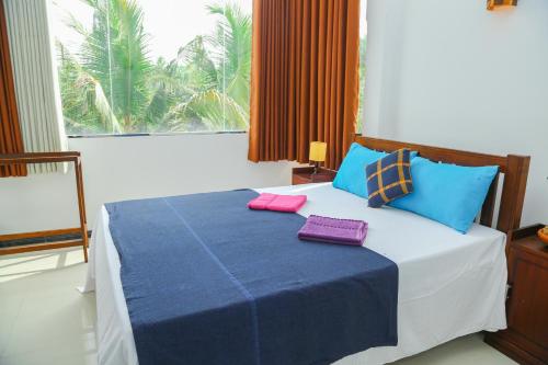 The Heavens Ocean Villa Talpe في تالبي: غرفة نوم مع سرير مع وسائد زرقاء وأرجوانية