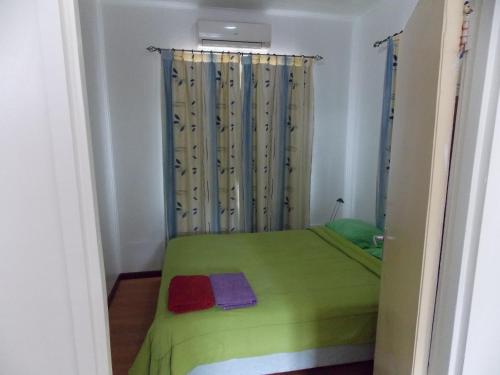 a small bedroom with a green bed with a window at At Rachel in Paramaribo