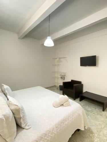 a white bedroom with a bed and a television at Patio de Getsemani in Cartagena de Indias