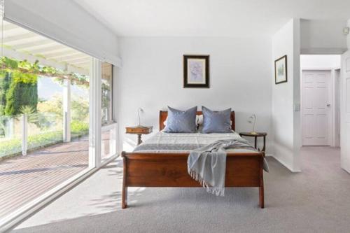 a bedroom with a bed and a large window at Milla's Vineyard Estate in Pokolbin