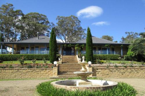 a home with a fountain in front of a house at Milla's Vineyard Estate in Pokolbin