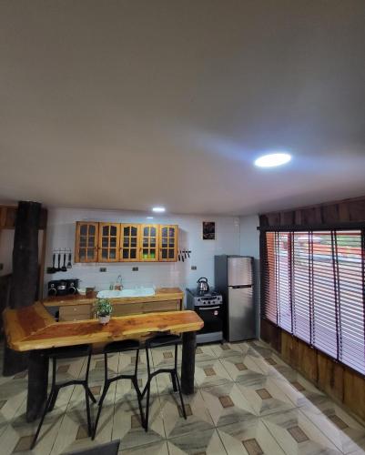 cocina con mesa de madera y nevera en Cabañas Condominio El Bosque en Pucón