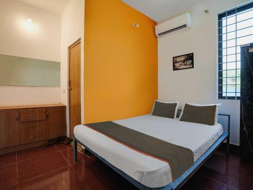 una camera con un letto e una parete gialla di OYO Collection O Grand Residency ad Auroville