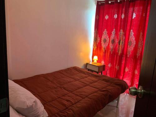 a bedroom with a bed with a red curtain at Uptown Condominium Primavera Residences in Cagayan de Oro