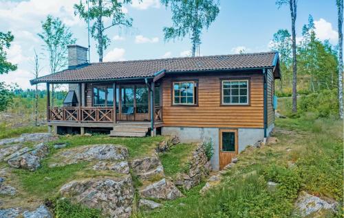 a log home with a large deck on a rock at Cozy Home In Gislaved With Sauna in Askebo