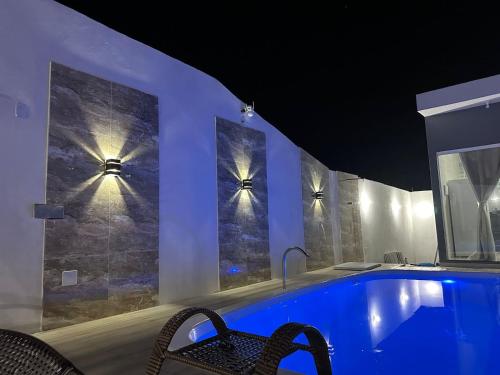 una piscina con 2 sillas y luces en la pared en Jacuipe Sun House, en Camaçari