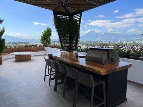 uma cozinha exterior com um bar com cadeiras e uma mesa em Rincon Moderno cerca aeropuerto em Guatemala