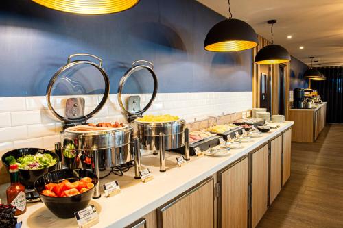 a buffet line with pots and pans of food at Holiday Inn Express Paris-Canal De La Villette by IHG in Paris