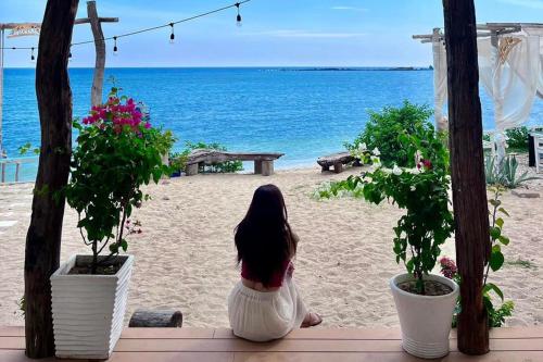 a woman sitting on a porch looking out at the beach at Chiu Chiu Resort Đảo Phú Quý in Cu Lao Thu