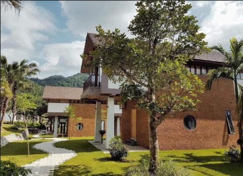 dom z drzewem przed nim w obiekcie Thang Mây Village Resort w mieście Ba Vì District
