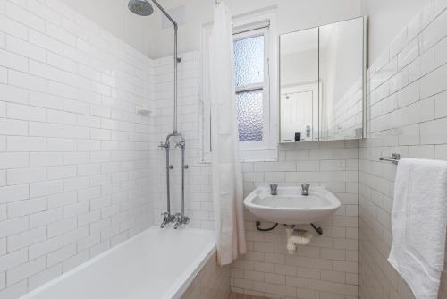 a white bathroom with a sink and a bath tub at Luxe-Coastal Balmoral Beachfront Apartment in Sydney