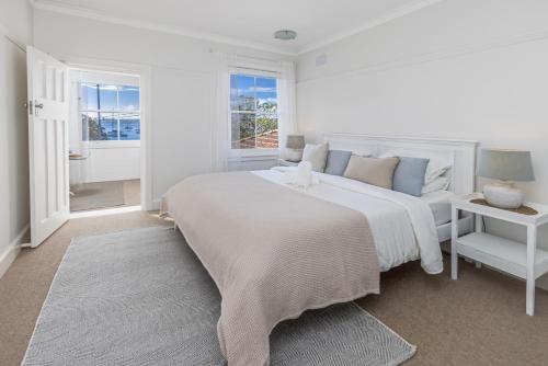 um quarto branco com uma cama grande e uma janela em Luxe-Coastal Balmoral Beachfront Apartment em Sydney