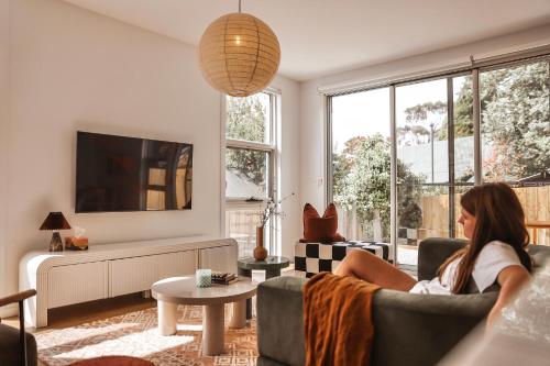 a woman sitting on a couch in a living room at Architect Home with View in Central Hobart in Hobart