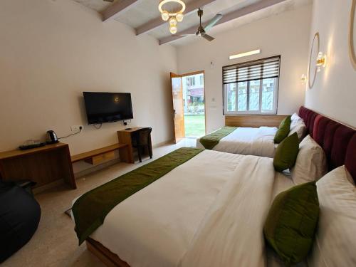 a bedroom with two beds and a flat screen tv at Hotel Utsav Grand in Varanasi