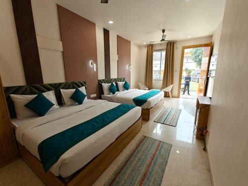a hotel room with two beds with blue pillows at Hotel Utsav Grand in Varanasi