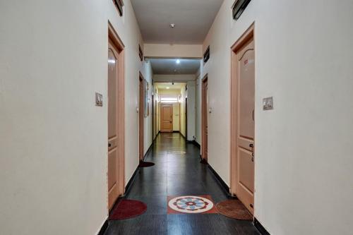 a hallway with white walls and wood floors and a door at OYO Flagship Jashwanth Residency in Mysore