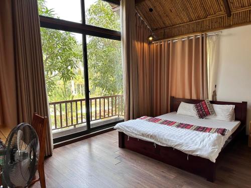 a bedroom with a bed and a large window at Thang Mây Village Resort in Ba Vì