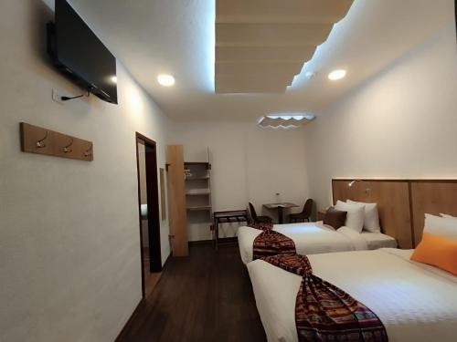 a hotel room with two beds and a flat screen tv at Casona Tobar Hotel in Rocafuerte