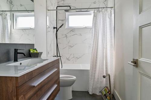 a white bathroom with a sink and a toilet at Villa luxueuse avec vue sur le fleuve Villa GrandeCasa in Trois-Rivières