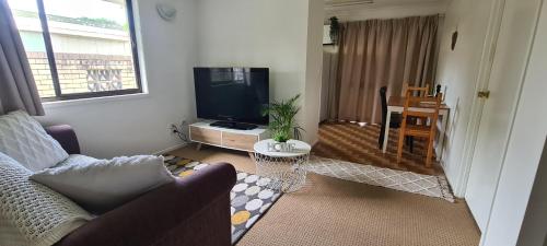 a living room with a couch and a tv at Guesthouse in fantastic location in Brisbane