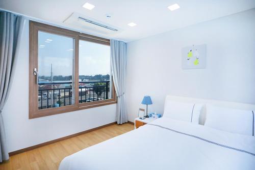 ein Hotelzimmer mit einem Bett und einem Fenster in der Unterkunft The Naeun Stay in Seogwipo
