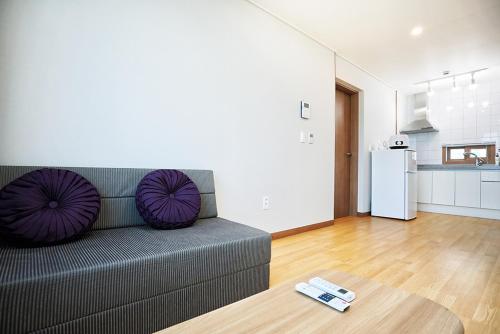 ein Wohnzimmer mit Couch und Küche in der Unterkunft The Naeun Stay in Seogwipo