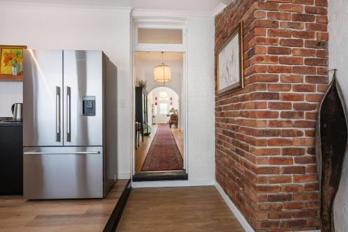 a kitchen with a brick wall and a refrigerator at Luxury at Lauralla - An Elegant Victorian Escape in Mudgee