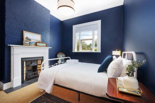 a blue bedroom with a bed and a fireplace at Luxury at Lauralla - An Elegant Victorian Escape in Mudgee