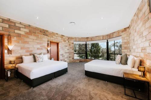 two beds in a room with a brick wall at 'Tyalla Lodge' Unique Luxe Design in the Mountains in Mudgee