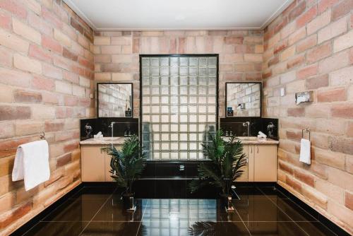 a bathroom with two sinks and a brick wall at 'Tyalla Lodge' Unique Luxe Design in the Mountains in Mudgee