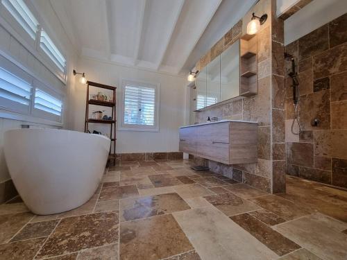 baño grande con bañera y lavamanos en Pipeclay Cottage - Farmstay Vibes and Chic Design, en Eurunderee