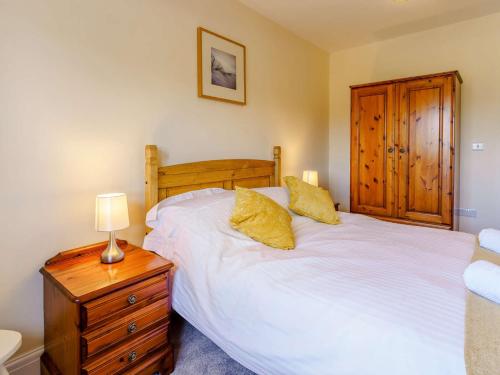 a bedroom with a white bed and a wooden cabinet at 3 Bed in Lampeter 86506 in Cellan