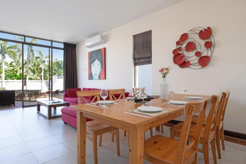 a dining room and living room with a wooden table and chairs at Pool Access Villa Argent 8, 3-Bedroom near Mission Hills Golf in Thalang
