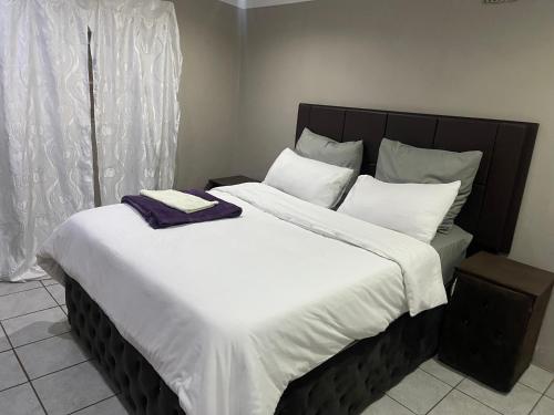 a large bed with white sheets and a purple towel on it at Moon Memories Guesthouse in Welkom